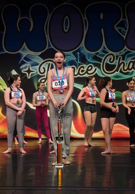 Dancer reacting with surprise as her routine places first, in front of the Work It backdrop