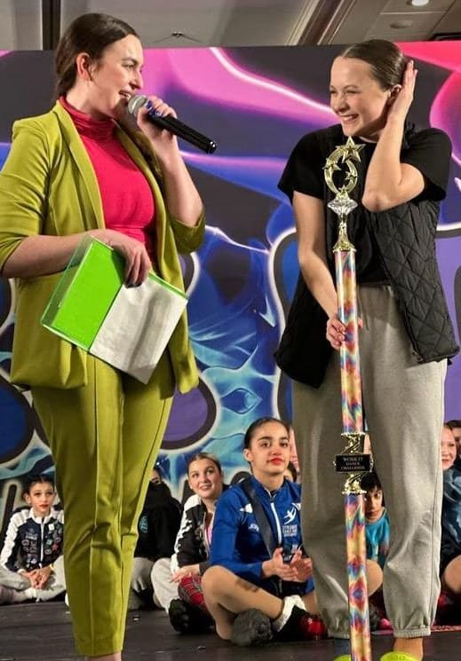 Work It host interviewing a dancer holding her trophy on stage