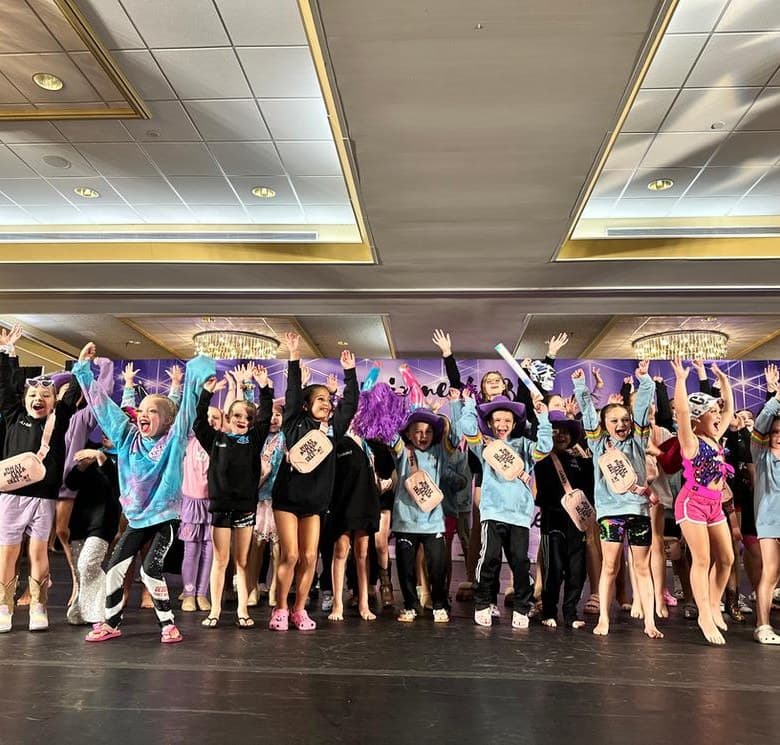 Young dancers jumping and cheering together on stage