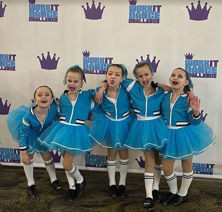 Five young dancers in blue tutus posing at the Work It step-and-repeat