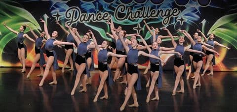 Large group performing a lyrical routine in front of the Work It Dance Challenge backdrop