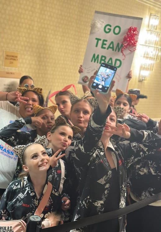 Studio team taking a group selfie with a Go Team sign
