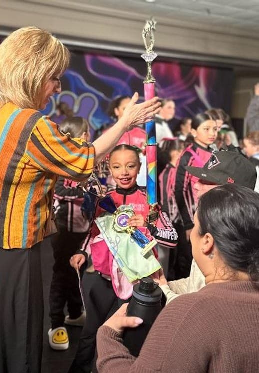 Young dancer receiving a trophy from a WIDC staff member